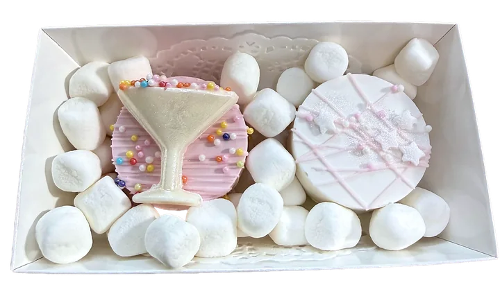 Gift box with a white chocolate martini glass and pink sprinkled treats among marshmallows
