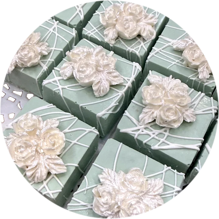 Close-up of sage green chocolate squares crowned with pearl-white roses