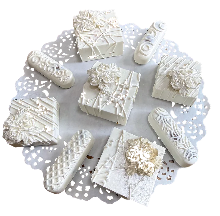 All-white chocolate bonbons with sculpted roses and gold pearls on a lace doily